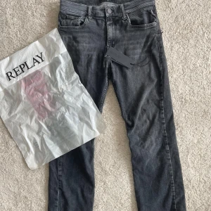 Svarta Replay jeans, Straight/Slim - Snygga svarta jeans från Replay med tvättad och något sliten look. Klassisk femficksmodell, raka ben och detaljerade bakfickor med Replay-logga. Jeansen har Straight/Slim passform och är tillverkade i mjukt denimtyg för en bekväm känsla.