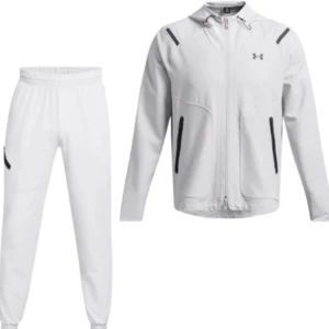 Vit träningsdress från Under Armour - Snygg vit träningsdress från Under Armour med svarta detaljer. Setet består av en zip-jacka med huva och matchande byxor med resår i midjan och vid benslut. Perfekt för dig som gillar sportig stil och vill sticka ut på gymmet. Använd i 1 månad och är helt ny dom är storlek S men passar perfekt för dig som använder M är själv 194 cm och dom passar mig perfekt.