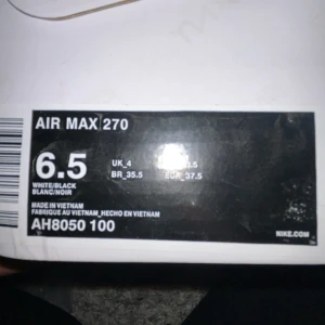 Nike Air Max 270 vit/svart strl 37.5 - Nike Air Max 270 sneakers i vitt med svarta detaljer och stor synlig Air-enhet i hälen. Snygg och modern design med mesh-överdel och klassisk Nike-logga på sidan. Perfekta för dig som gillar streetstyle och komfort.