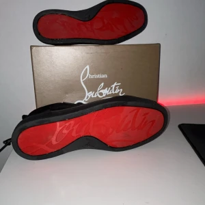 Svarta sneakers från Christian Louboutin - Säljer ett par svarta sneakers från Christian Louboutin med ikonisk röd sula och snygg signatur. Skorna har rund tå, snörning och är tillverkade i mocka med skinnfoder. Perfekt för dig som vill sticka ut med exklusiv stil och lyxiga detaljer. Skriv dm om du är intresserad eller vill ha info, Skorna kan tvättas innan köp. Pris kan diskuteras, 