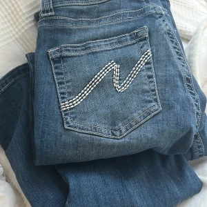 Blå stitch jeans från Nelly - Snygga blå jeans från Nelly med bootcut/flare passform. Jeansen har dekorativ vit brodering på bakfickan och dubbla silverfärgade knappar fram. Materialet är stretchigt och färgen är mellanmörkblå💞🩷🙌👏😽