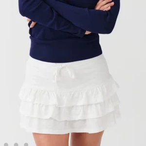 Vit volangkjol från Gina Tricot  - Supersöt vit kortkjol från Gina Tricot i storlek XS. Kjolen har flera lager med volanger och en snörning i midjan. Super gullig och i perfekt skick! Använts fåtal gånger.