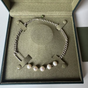 Rebel Pearl Necklace Maria Nilsdotter - Unikt halsband från Maria Nilsdotter med chunky silverfärgad kedja, säkerhetsnål-detalj och sex stora vita sötvattenspärlor. Snygg kontrast mellan det råa silvret och de klassiska pärlorna. Kommer i originalask med certifikat. 