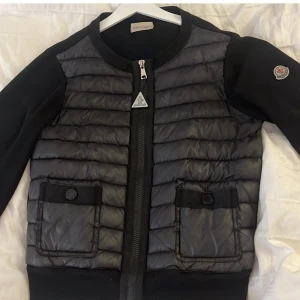 Svart pufferjacka från Moncler - Hade gärna kunnat byta för ett par svarta isabel marant skor! Äkta snygg svart pufferjacka från Moncler med quiltad front och två fickor med knapp, inga defekter. Passar S/XS/XXS. Säljer då den inte kommer till användning längre. 