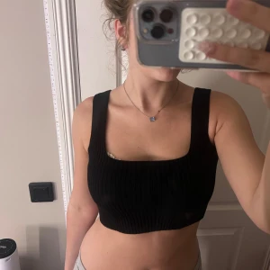 Svart ribbad croppad linnetopp - Säljer en svart croppad linnetopp med breda axelband och fyrkantig urringning. Toppen är ribbad och sitter tight mot kroppen, perfekt för att styla med låga jeans eller kjol. Enkel och stilren design som funkar till mycket. Skönt inför sommaren! 😍