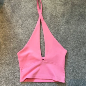 Rosa ribbad croppad linnetopp - Säljer en snygg rosa croppad linnetopp med ribbad struktur och djup v-ringning framtill. Det är mjukt o stretchigt material. Några fläckar som visas på bild 3 och 4