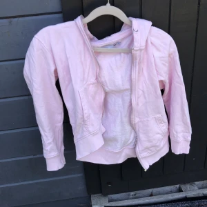 Ljusrosa hoodie från 157 med dragkedja - Säljer en ljusrosa hoodie från 157 i storlek 140. Tröjan har huva, långa ärmar och praktisk dragkedja framtill. Mjuk insida i frotté och två fickor på sidorna. Perfekt för dig som gillar chill och comfy stil.