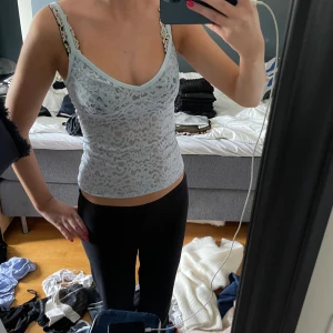 Ljusblå spetsig linnetopp med v-ringning - Säljer en ljusblå linnetopp med v-ringad hals och tunna axelband. Toppen är i genombruten spets med ett snyggt mönster och sitter tight mot kroppen. Perfekt för dig som gillar en feminin och trendig look.