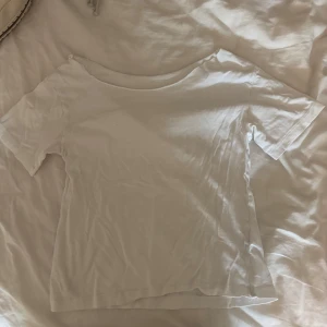 Vit off sholder tröja  - En enkel vit t-shirt med rundad hals och korta ärmar. Modellen är klassisk och har en rak passform, perfekt att matcha med jeans eller shorts. Materialet känns mjukt och lätt, troligtvis bomull. Snygg att ha som lager eller solo.