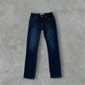 Levi's 512 Slim Taper jeans mörkblå - Mörkblå Levi's 512 Slim Taper jeans med klassiska kontrastsömmar och femficksdesign. Snygg, smal passform som smalnar av nedtill. Ikonisk läderpatch bak i midjan och röd Levi's-tag på bakfickan. Perfekta jeans för en clean och stilren look. Dom är nästan helt oanvända!