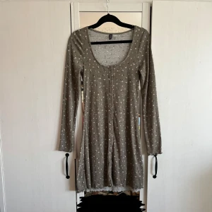 Grön blommig klänning - Supersöt grön långärmad kortklänning med små rosa blommor från H&M i strl S. Klänningen är ribbad och har rundad halsringning samt knappar hela vägen ned framtill (enbart den första högst upp går att knäppa upp)!💞