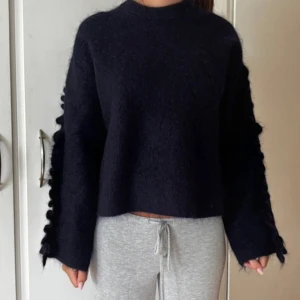 Mörkblå fluffig stickad tröja Arket - Säljer en mörkblå stickad tröja i storlek S med loose passform. Tröjan har långärmade ärmar och coola volangdetaljer längs sidorna av ärmarna. 