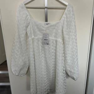 Vit studenklänning/examensklänning - Säljer denna supersöta och bekväma klänning som är från kollektionen Lojsan Wallin x NAKD som är helt slutsåld då storleken tyvärr inte passade mig. Helt oanvänd och prislappen sitter kvar. Perfekt klänning som passar inför student/skolavslutning. Storlek 38