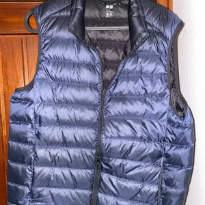 Blå dunväst från Uniqlo - Säljer en snygg blå dunväst från Uniqlo. Västen har en dragkedja framtill och är perfekt för lager-på-lager under kyligare dagar. Den är lätt och smidig, vilket gör den praktisk för olika väderförhållanden. Original pris ligger på 600kr och jag säljer denna näst intill nya väst som bara använde 1 sommar för 350kr