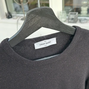 Brun tröja från Gran Sasso - Säljer en stilren brun tröja från Gran Sasso. Tröjan har en klassisk rund hals och långa ärmar, perfekt för kyligare dagar. Den är tillverkad i ull vilket gör den varm och skön. Passar utmärkt till både vardag och mer uppklädda tillfällen.