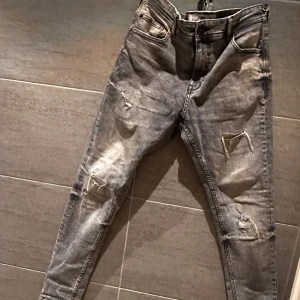 Grå slim jeans  - Snygga grå jeans med slitningar för en trendig look. De har en skinny passform och är midwaist. Perfekta för en avslappnad stil med en edgy touch.