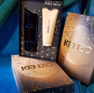 Kenzo parfymset - Elegant parfymset från Kenzo med en mörkblå flaska och en matchande vit tub. Förpackningen har ett stilrent designmönster med guldiga detaljer och Kenzo-loggan i centrum. Perfekt för den som vill ha en lyxig doftupplevelse.