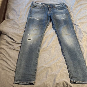 Slim fit jack n jones 31/32 - Snygga blå jeans med coola slitningar och en klassisk femficksdesign. Perfekta för en avslappnad stil. De har en knappgylf och är i en slim passform.