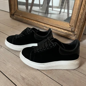 Svarta sametts sneakers från Alexander McQueen - Snygga svarta sametts sneakers från Alexander McQueen med vit sula och klassisk snörning. Väldigt bra skick.
