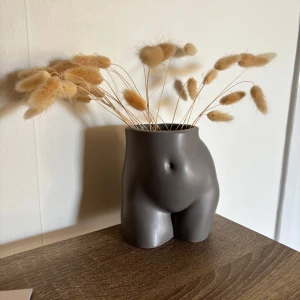 Dekorativ vas i form av en kropp - Unik och stilren vas i form av en kropp, perfekt för att ge en konstnärlig touch till ditt hem. Vasen är i en elegant grå färg och passar utmärkt för torkade blommor eller som en skulptural inredningsdetalj.