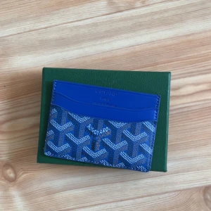 Blå korthållare med mönster - Säljer ett stilrent blått kortfodral. Perfekt för att hålla dina kort organiserade och lättillgängliga. Kommer i en elegant grön förpackning.