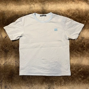 Acne Studios T-shirt  - Säljer denna stilrena ljusblå t-shirt från Acne Studios. Bra basic T-shirt med acnes klassika logga på bröstet. Helt ny utan taggar. Skriv om ni undrar något!