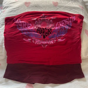 Red y2k tubetop - Snygg röd tubtopp från Morgan med ett coolt tryck i lila och rosa. Perfekt för en avslappnad stil eller att styla upp för en utekväll. Toppen är ärmlös och har en bekväm stretchig passform. det är även dubbelt med tyg så ingen nipslip💘😋