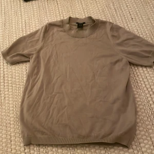 Beige tröja från Lindex - Säljer en stilren beige tröja från Lindex. Tröjan har korta ärmar och en rund halsringning med ribbade kanter. Perfekt för en avslappnad look. 