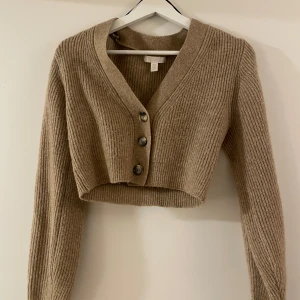 Beige ribbad kofta - Säljer en beige ribbad kofta med v-ringning och knappar framtill. Den är croppad och har långa ärmar! Jätte cute men måste rensa 🥹✨🪩⭐️