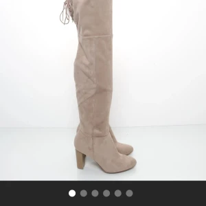 Beige overknee stövlar från H&M - Snygga beige overknee stövlar från H&M i mocka med snörning baktill. De har en klack och en rund tå, vilket ger en stilren look. Perfekta för att höja din outfit till nästa nivå. De har någon lite smutsfläck men inget man tänker på vid intresse kan jag skicka närmare bilder❤️