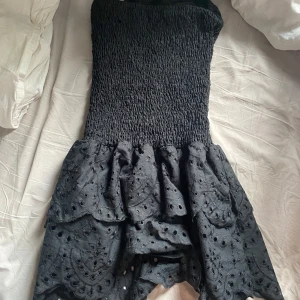 Svart axelbandslös klänning med volang - Svart klänning. Aldrig använd men omsydd så den sitter sitter tajtare super fin 