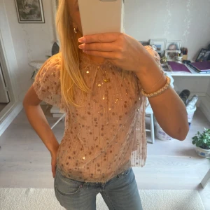Rosa glittrig blus med volangärmar - Säljer denna ljusrosa blus med glittriga paljetter och volangdetaljer på ärmarna. Sååå fin💕💕 köpt för 500kr