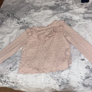 Ljusrosa volangtröja från Kappahl - Säljer en ljusrosa långärmad tröja från Kappahl med volangdetalj framtill. Tröjan har ett diskret mönster i tyget. Den är nästan helt ny använt 3 gånger.