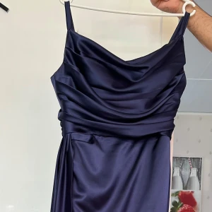 Mörkblå långklänning i satin - Hej! Jag säljer min mammas klänning hon har använt 1 gång. Den har inga fläckar eller skador och sitter som ett smäck.   Priset är 1700, storleken är 44 men är mer som 42. För mer frågor skriv gärna till mig och jag bor i Eslöv om man vill träffas. 