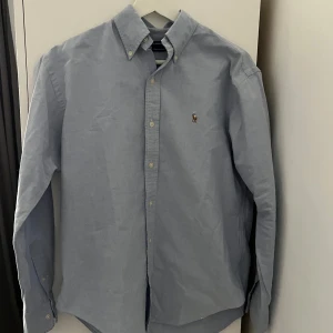 Ralph Lauren Skjorta - Säljer en ljusblå Ralph Lauren skjorta som är i väldigt bra skick, inte använd mycket. Den är i storlek XS/S. Priset kan diskuteras vid snabb affär. Jag står ej för leveransstrul. Hör av er vid frågor!