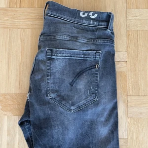 Dondup Jeans - Säljer dessa fräsha svart/gråa jeans från Dondup med snyggt slitage på benen. Säljer pga hål vid skrevet, hålet är inte öppet och går förmodligen att lappa ihop. Pris kan diskuteras!