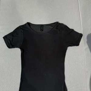 Svart t-shirt från twilfit - En svart t-shirt med rund halsringning och korta ärmar. T-shirten har en tight passform och är i ett mer genomskinligt material från twilfit. Storlek S 