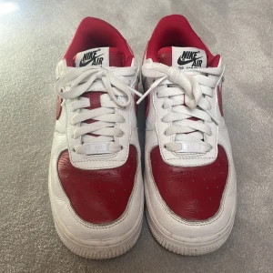 Nike Air Force 1 Low röd/vit - Säljer ett par Nike Air Force 1 Low i vitt och rött skinn. Klassisk modell med röd swoosh och detaljer, vit sula och snörning. Perfekta sneakers för dig som gillar en sportig och stilren look. Egen design på Nikes hemsida. Köpta för 3 år sedan. Inte använda mycket. 
