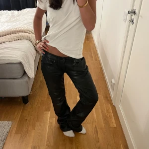 Svarta skinnbyxor från Laget 157 - Snygga svarta skinnbyxor från Lager 157 med klassisk femficksmodell och raka ben. Byxorna har bälteshällor, knapp och dragkedja framtill. Perfekta för dig som vill ha en edgy och trendig look.💖