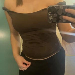 Brun off shoulder top från Gina Tricot - Säljer en brun, tight offshoulder top från Gina Tricot. Den har rynkade detaljer på ena sidan och är tillverkad i mjukt stretchigt material. Perfekt för dig som vill ha en trendig och stilren look.