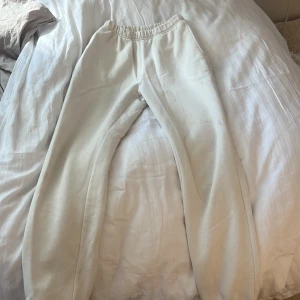 Vita mjukisbyxor från Gina Tricot - Säljer ett par vita mjukisbyxor från Gina Tricot, basically basics-kollektionen. Byxorna har resår i midjan och vid bensluten för en bekväm passform. Perfekta för en avslappnad stil.