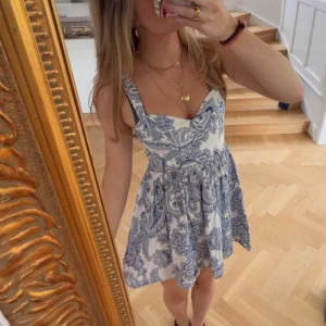 Vit och blå kortklänning från Zara - Supersöt kortklänning som inte finns att köpa på ZARA längre. Den har blått paisleymönster på vit botten. Klänningen har smala axelband, markerad midja och lätt utställd kjol. Perfekt till sommaren!💕