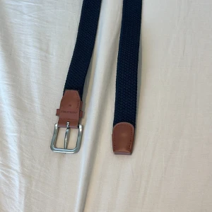 Mörkblå flätat bälte från Jack and jones - Snyggt mörkblått flätat bälte från KappAhl med detaljer i brunt skinn och silverspänne. Perfekt accessoar för att lyfta din outfit. Klassisk design med stilrena detaljer. Inga defekter och som ny! Skriv vid fundering 💭 😁