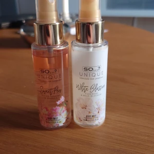 So...? Unique Body Mist Sweet Pea & White Blossom - Två body mists från So...? Unique-serien. En med doft av Sweet Pea, vattenjasmin och vanilj i rosa flaska med blommotiv, och en med doft av White Blossom, tuberos och päronblomma i vit flaska med blommotiv. Båda har guldfärgade spraymunstycken och rymmer 50 ml.