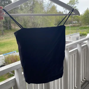 Svart linnetopp från Gina Tricot - Säljer en enkel och stilren svart linnetopp från Gina Tricot. Toppen har tunna axelband och rak skärning, perfekt att matcha med jeans eller kjol. Materialet känns mjukt och följsamt.