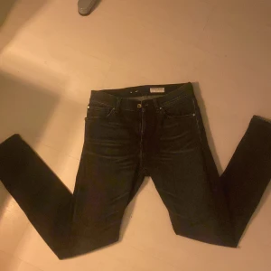 Svarta jeans från Tiger of Sweden - Snygga svarta jeans från Tiger of Sweden med klassisk femficksdesign och raka ben. Byxorna har normal passform och är tillverkade i ett mjukt jeanstyg. Perfekta för en stilren look. Dom är använda en gång och går som ny skick. Storlek 30/32
