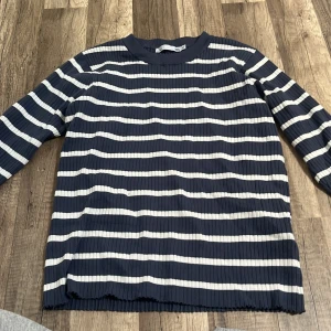 Mörkblå och vit randig ribbad tröja från 157 - Säljer en ribbad långärmad tröja från 157 i mörkblått och vitt med horisontella ränder. Tröjan har rund halsringning och är tillverkad i ett stretchigt material som sitter bekvämt på kroppen.