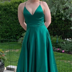 Balklänning - En fin grön balklänning från JJsHouse. Krossad rygg men justerbara snören och vadderade kupor. Jag är 160 cm och den är för lång MED klackar på. Är i storlek S men den är justerbar så passar M och XS också! Har ett litet märke längst ner på klänningen som knappt syns (bild 3). Den är kemtvättad!