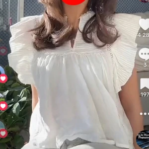 Vit blus med volang - Säljer en söt vit blus med volangdetaljer på axlarna och längs bröstet. Blusen har korta ärmar och knappar framtill. Perfekt för en fräsch och somrig look.🩵🩵🩵