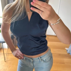 Mörkblå topp med rosett - Säljer en mörkblå  topp med snygg rosett i ryggen från bikbok. Nyskick 